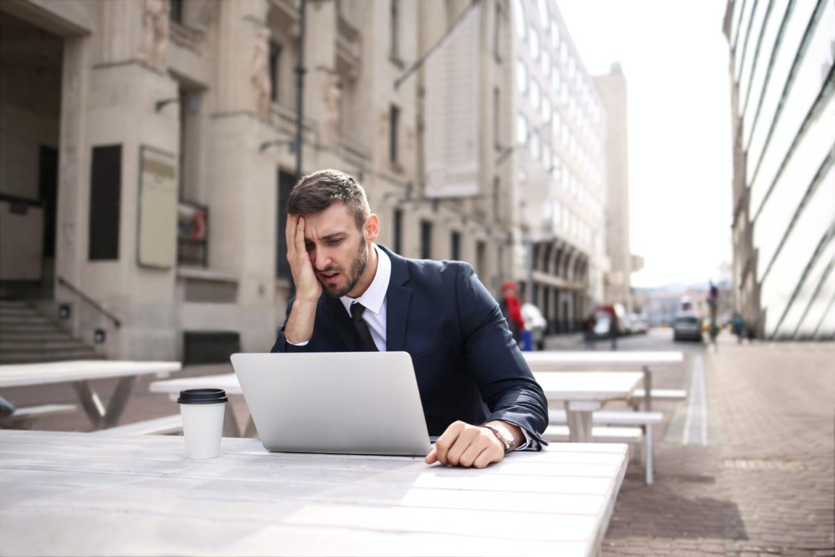 Image of a young man looking at his laptop in dispair